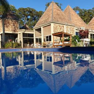 a house with a swimming pool in front of it at Sanctuary Resort Motor Inn in Coffs Harbour