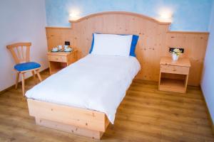 a bedroom with a bed with a wooden headboard and a chair at Agritur Val d'Adige in Trento