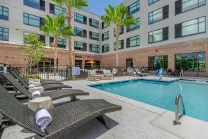 a swimming pool with chairs and a building at Cambria Hotel Charleston Riverview in Charleston