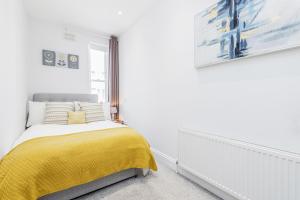 2-bed Notting Hill / Portobello في لندن: غرفة نوم بسرير وبطانية صفراء