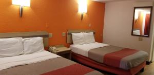 2 camas en una habitación de hotel con paredes de color naranja en FairBridge Inn Express London, en London