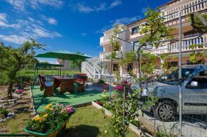 a garden in front of a building with a table and umbrella at Apartment Branko in Lopar