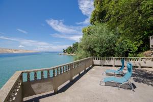 2 sedie blu sedute su un balcone vicino all'acqua di Apartments By the sea in Lopar a Lopar