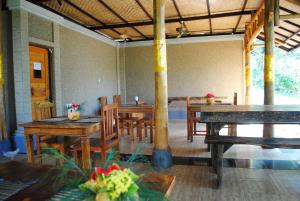 Tiara Homestay Pemuteran Bali في بيموتيران: غرفة طعام مع طاولات وكراسي خشبية