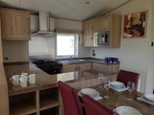 a kitchen with a table with chairs and a counter top at Mini lodge hot tub hols at Kingfisher Court in Tattershall