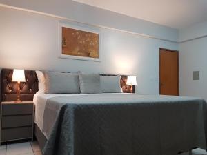 a bedroom with a bed with a blue blanket and two lamps at B & A Suites Inn Hotel - Quarto Luxo Diamond in Anápolis