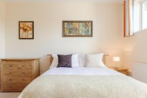 a bedroom with a large white bed and a dresser at Camstay Townhouse in Cambridge