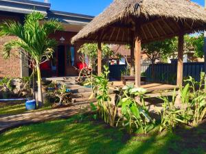 un portico con un ombrellone di paglia e alcune piante di Villa Dika Pemuteran a Pemuteran