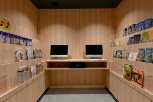 a library with two computer monitors on the wall at Vessel Hotel Campana Susukino in Sapporo