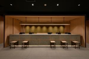 a lobby with a large counter with stools and chairs at Vessel Hotel Campana Susukino in Sapporo