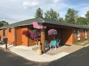 a cabin with an american flag and a porch with chairs at Northwoods Inn & Suites Minocqua in Minocqua