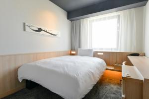 a bedroom with a white bed and a window at Vessel Hotel Campana Susukino in Sapporo