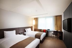 a hotel room with two beds and a television at Hotel Prumir in Hwaseong