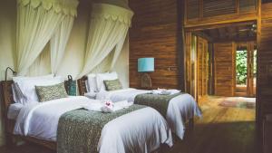Dos camas con gatos blancos en un dormitorio en Desa Saya Eco Luxury Resort & Spa, en Tejakula