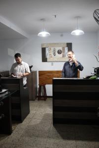 two men sitting at desks in an office at HOTEL PLAZA FERREIRA in Barra Mansa