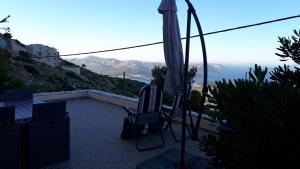 an umbrella and a chair on a patio with a view at Viva B&B in Anavissos