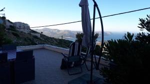 an umbrella and a chair on a patio with a view at Viva B&B in Anavyssos