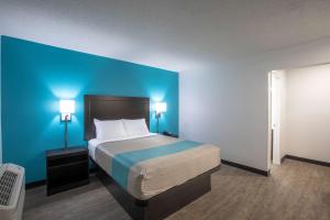 1 dormitorio con 1 cama grande y pared azul en Motel 6-Greenville, SC - I-85 Near Downtown, en Greenville