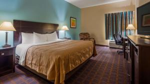 a hotel room with a bed and a desk at Red Lion Inn & Suites Blue Springs in Blue Springs +14 photos