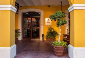 Best Western Hotel Madan في فيلاهيرموسا: مبنى أصفر أمامه نباتات خزف