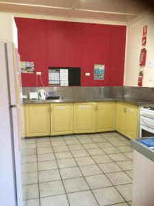 a kitchen with yellow cabinets and red walls at Arcadia Beach Guest House and Car Hire in Nelly Bay