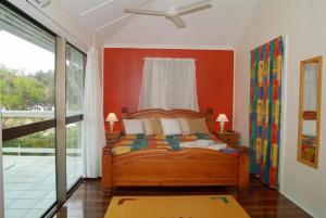 a bedroom with a bed with an orange wall at Arcadia Beach Guest House and Car Hire in Nelly Bay