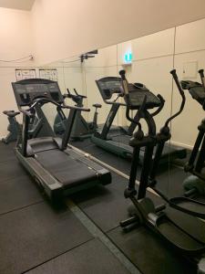 a gym with several tread machines in a room at Cosy City Apartment in Melbourne