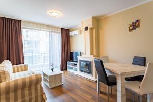a living room with a couch and a table and a television at Rose Gardens Apart Hotel in Pomorie