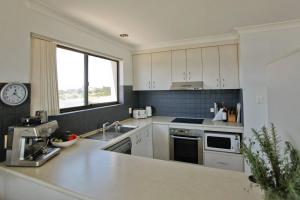 uma cozinha com armários brancos, um lavatório e uma janela em Vista Marina Penthouse #5 - Amazing views & location em Bermagui