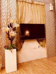 TV de pantalla plana en una pared con flores en un jarrón en Hiye Fashion Motel en Dounan