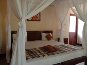a bedroom with a bed with white drapes at Bali Gecko Homestay in Pemuteran