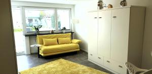 um sofá amarelo numa sala de estar com uma janela em Fewo Saur em Immenstaad am Bodensee