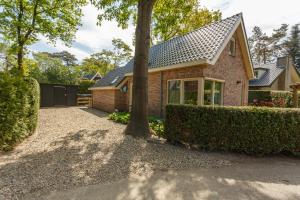 a brick house with a tree in the driveway at Villa Vlinder in Otterlo