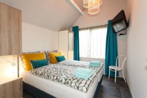 een slaapkamer met een groot bed met blauwe en gele kussens bij Villa Vlinder in Otterlo