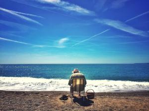 a man sitting in a chair on the beach at Villa du Cros in Cagnes-sur-Mer