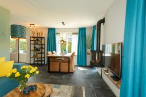 a living room with blue curtains and a television at Villa Vlinder in Otterlo