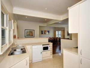 a kitchen with white cabinets and a sink in it at Summer Cottage in Hawks Nest +10 photos