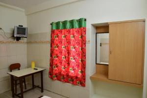 a room with a red shower curtain and a table at Hotel Ganesh Lodge in Kanyakumari