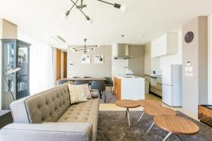 een woonkamer en een keuken met een bank en tafels bij Minn Umeda-North in Osaka