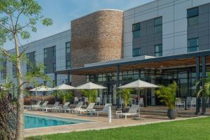 a hotel with a pool and chairs and umbrellas at Garden Court Kitwe in Kitwe