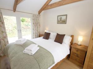 a bedroom with a bed with white sheets and a window at Roosters in Lostwithiel