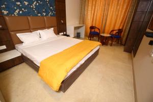 a bedroom with a large bed with a yellow blanket at Hotel Manbhavan in Mathura