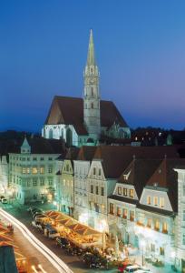 um grande edifício com uma torre de relógio e uma igreja em Stadthotel Styria em Steyr