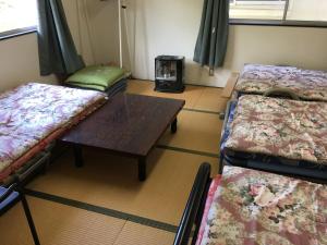 a room with three beds and a wooden table at Towadako Hostel in Towada