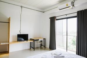 a bedroom with a desk with a computer and a window at PJ Loft Hotel in Ban Khok Krathin