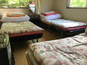 Habitación con 3 camas y almohadas. en Towadako Hostel en Towada