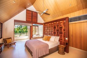 a bedroom with a large bed and a window at Niramaya Villas and Spa in Port Douglas