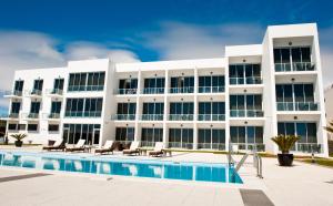 un grand bâtiment blanc avec une piscine dans l'établissement Atlantida Mar Hotel, à Praia da Vitória