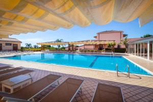 a swimming pool with chairs and an umbrella at La Terra Dei Sogni Country Hotel in Fiumefreddo di Sicilia