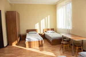 a room with two beds and a table and a desk at Monada Hotel & Hostel in Uzhhorod
